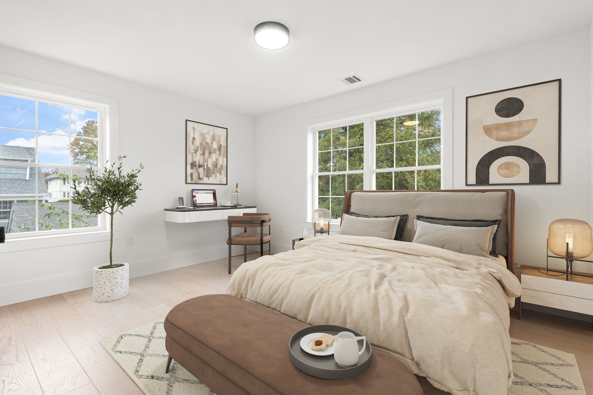 Bedroom with large windows, neutral color palette, bed, desk, artwork, and area rug.