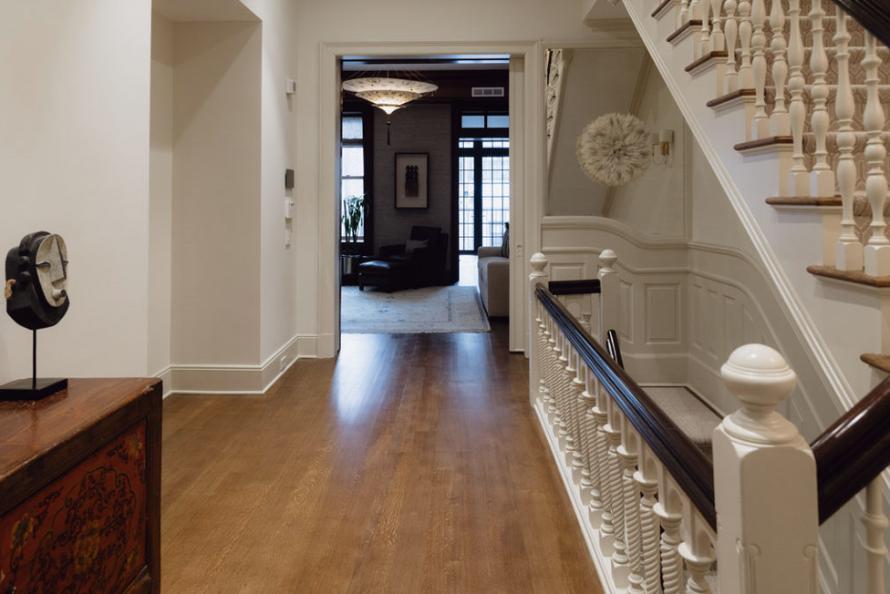 Entryway with hardwood floors, staircase on right, ornate balusters, view into a living room.