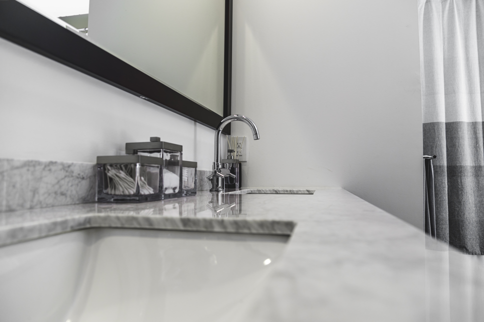 Bathroom sink with marble countertop, chrome faucet, and black-framed mirror.