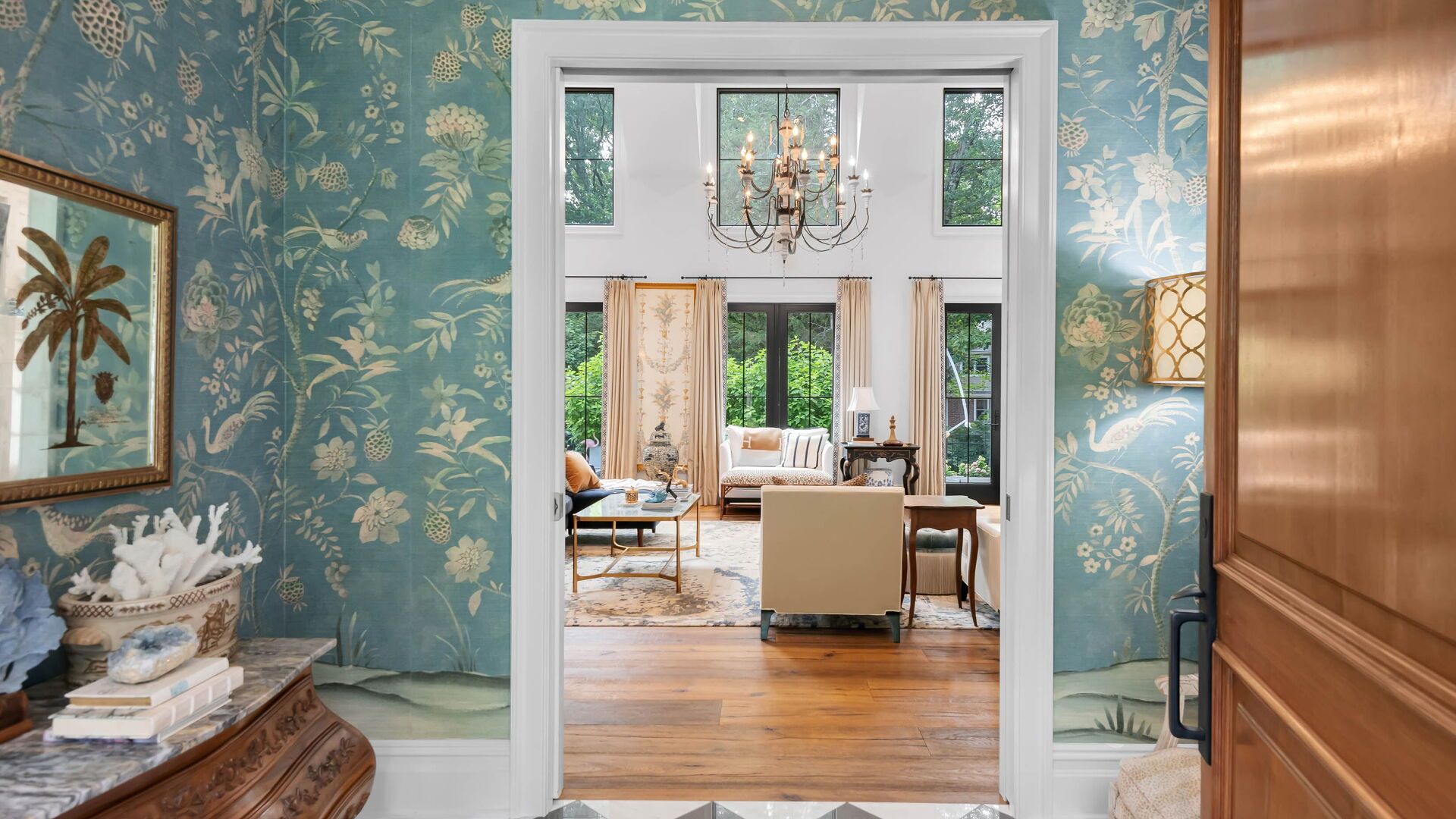 Elegant hallway with teal floral wallpaper, leading to a light-filled living room.