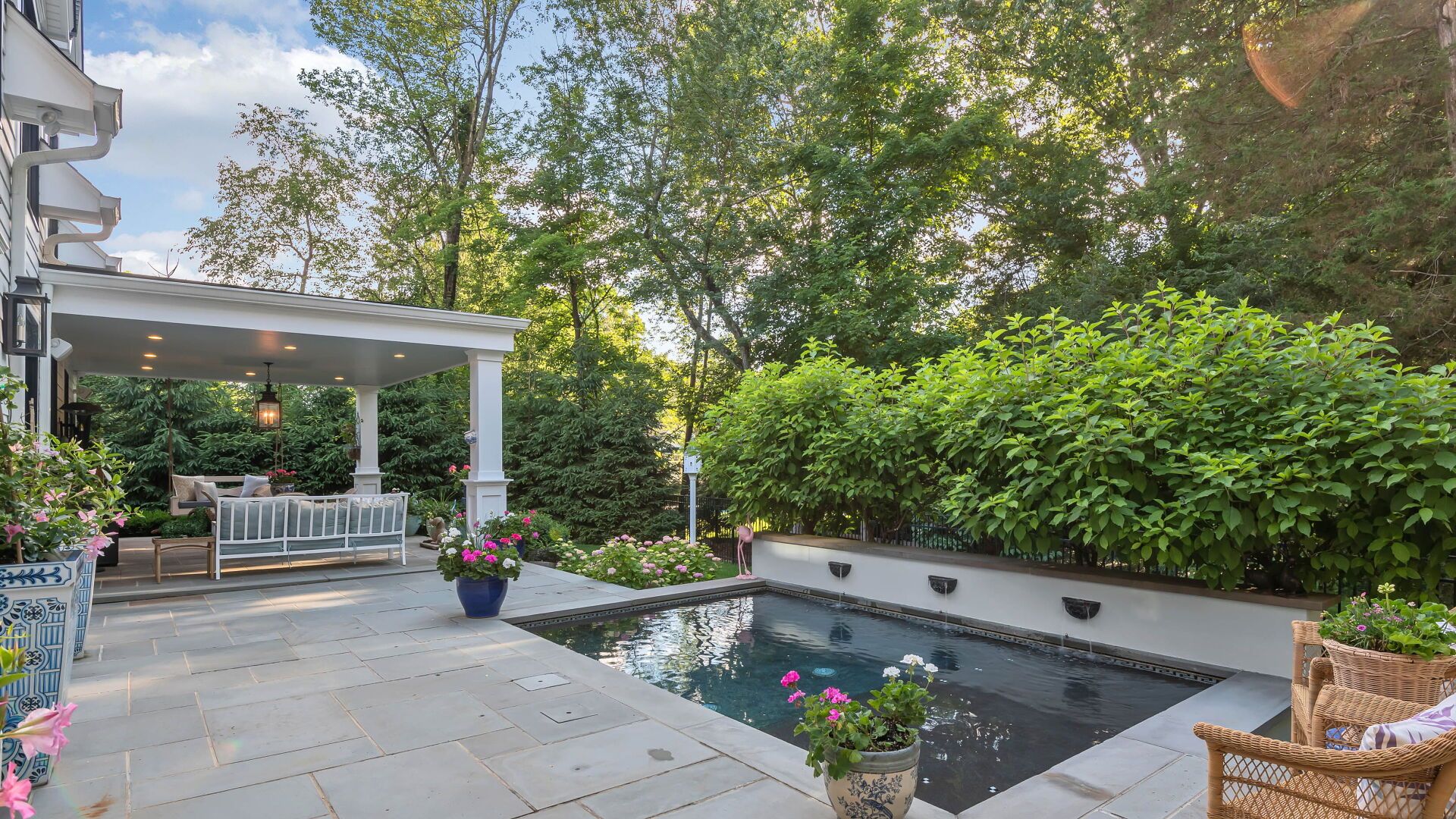 Backyard patio with small pool, pergola, and lush greenery.
