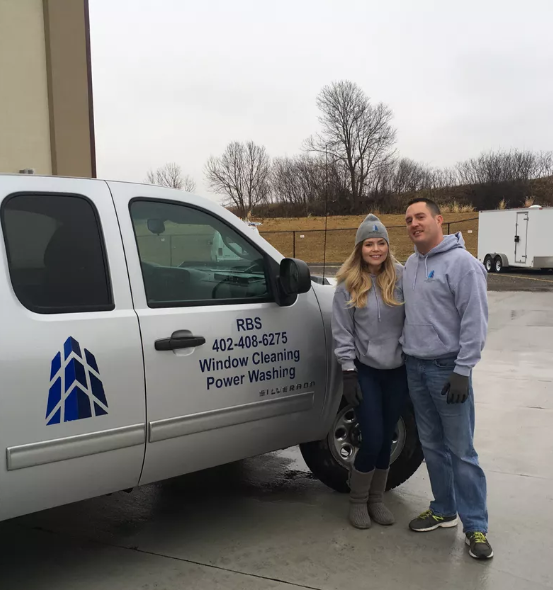 A man and a woman standing in front of a white truck