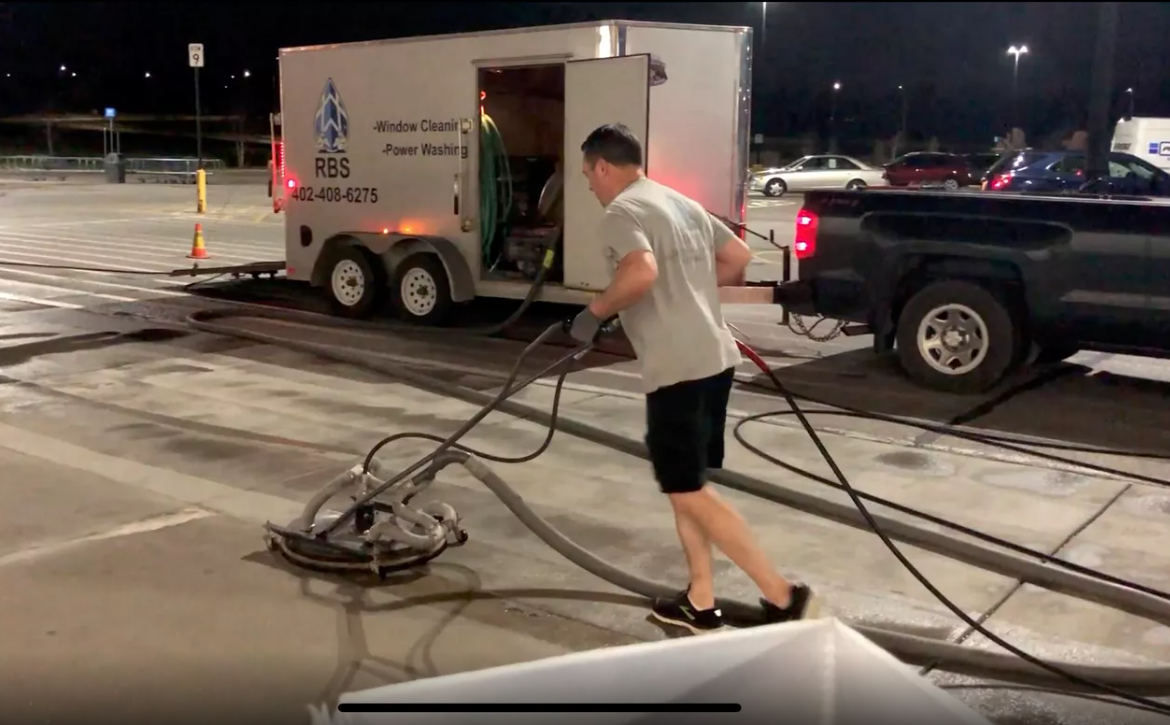 A man is cleaning a parking lot with a vacuum cleaner.