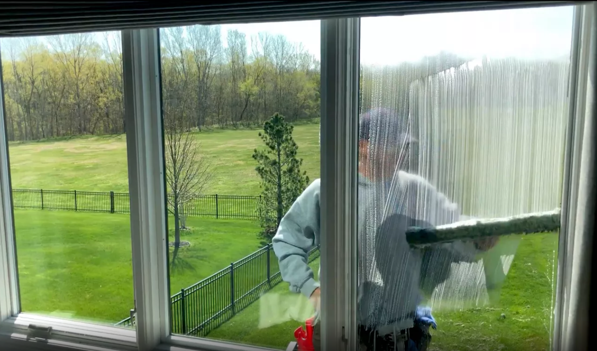 A man is cleaning a window with a vacuum cleaner.