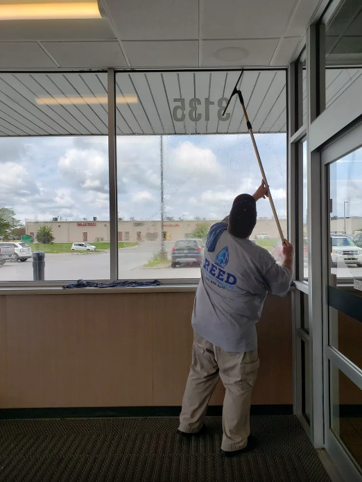 A man wearing a shirt that says feed is cleaning a window