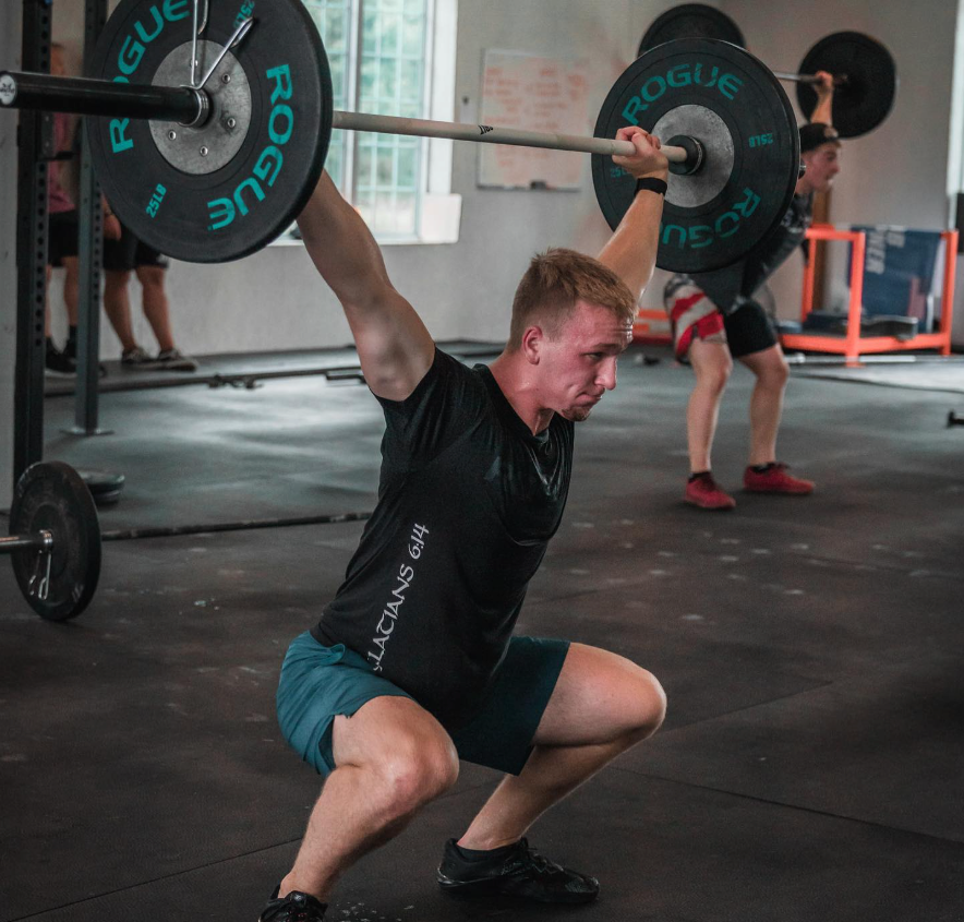 Man doing a barbell overhead squat at Power and Fitness gym in Bloomington, IL; lifting weight.