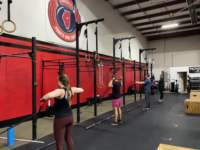 People exercising on pull-up rigs in a gym with red walls and black flooring