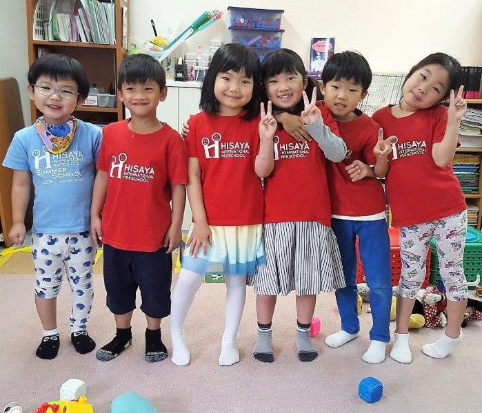 カラフルなシャツを着て、笑顔でピースサインをしている6人の子供たちの写真