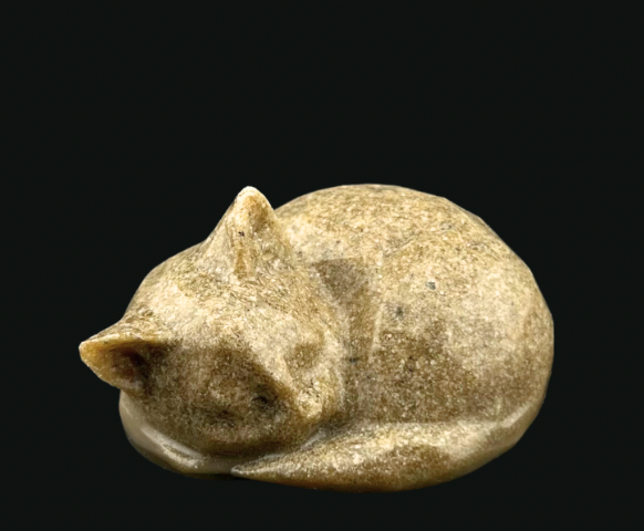 Small beige ceramic cat figurine curled up against a black background