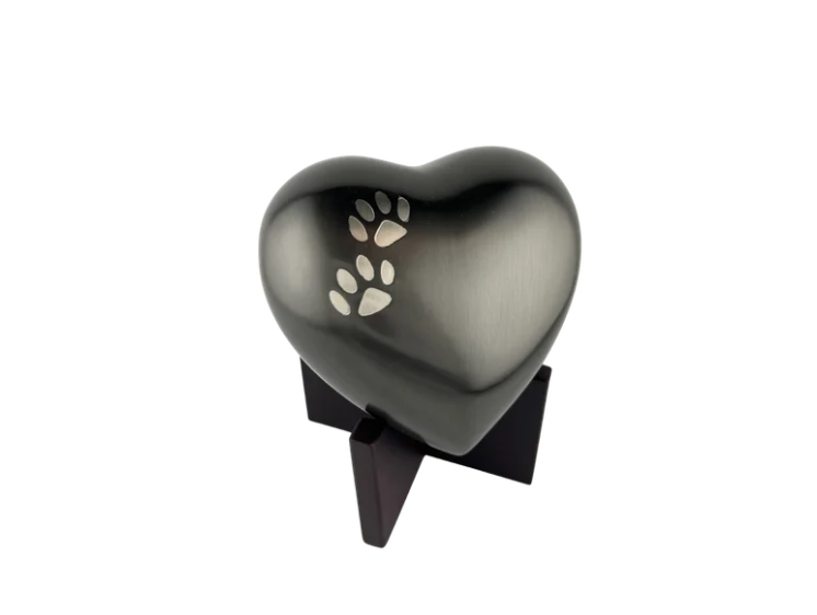 Black heart-shaped urn with white paw prints on a black stand