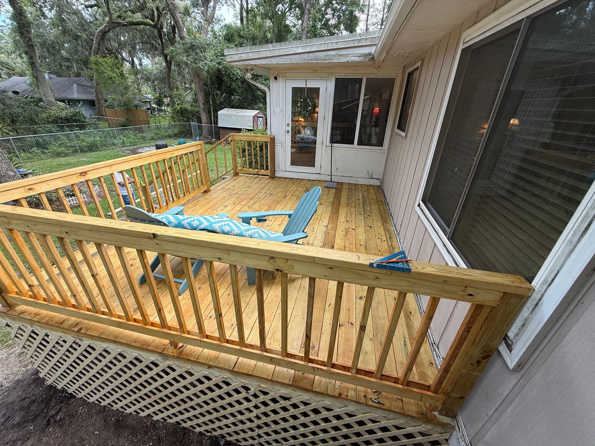 Wooden deck with railings, attached to a house with windows and a screened porch.