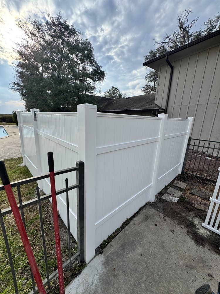 White vinyl fence next to a house and black metal fence.