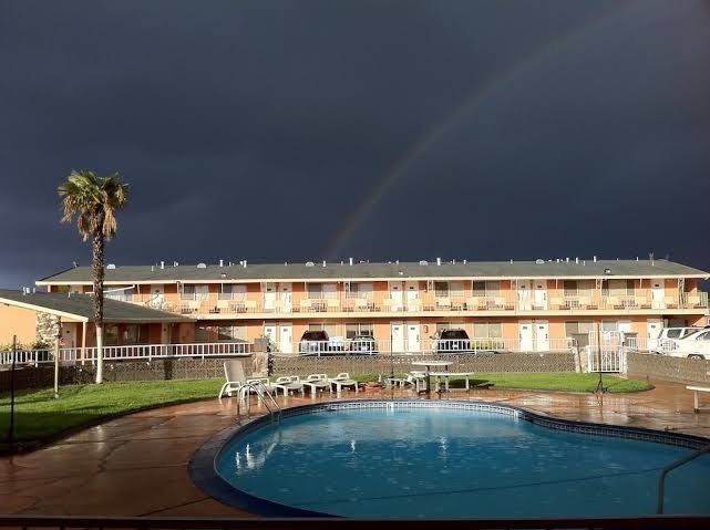 Motel courtyard with a pool under dark storm clouds and a rainbow in the sky