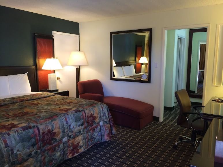 Hotel room with two beds, lamps, chair, mirror, and desk chair