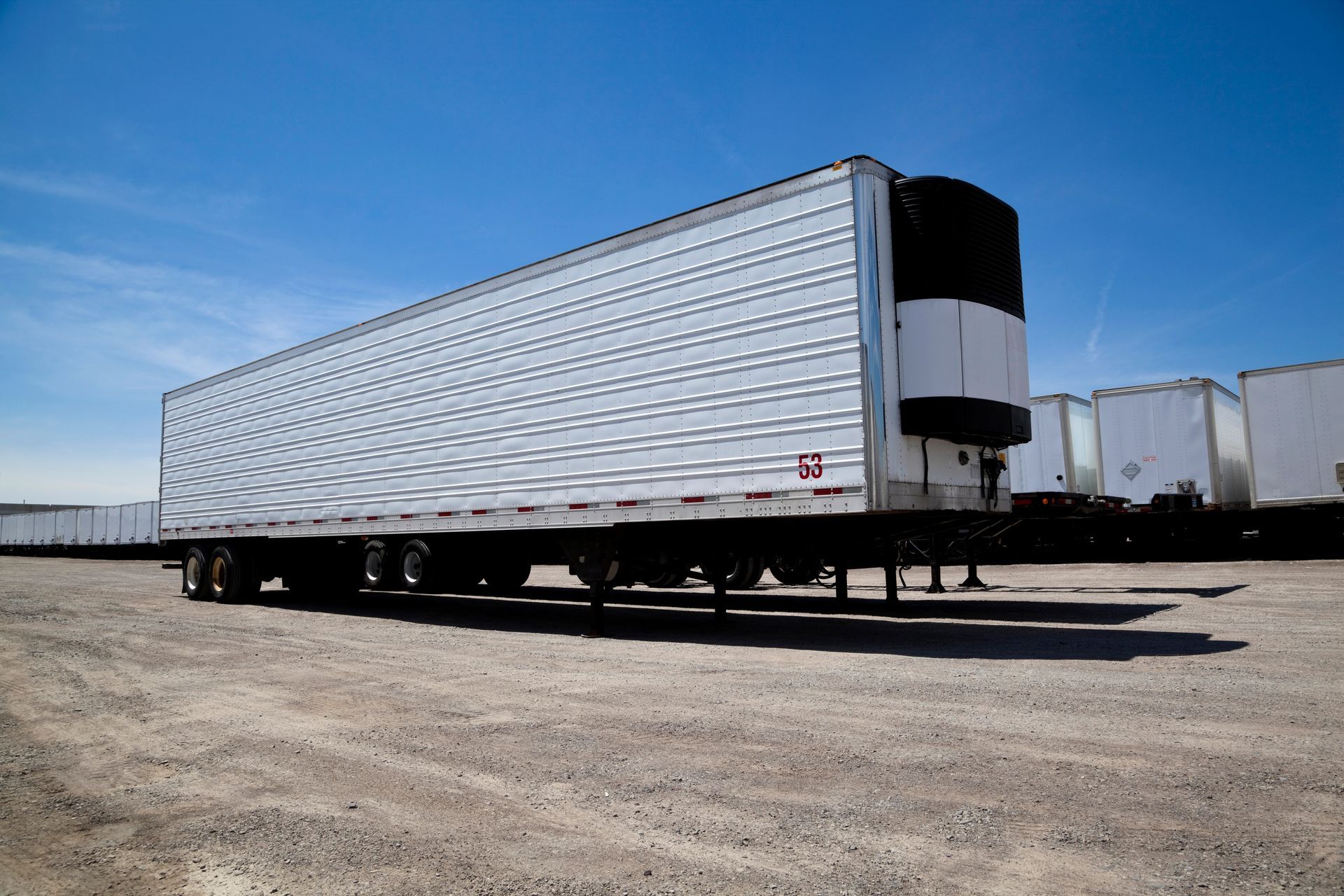 Transport truck trailer sitting in yard with a row of trailers behind it.