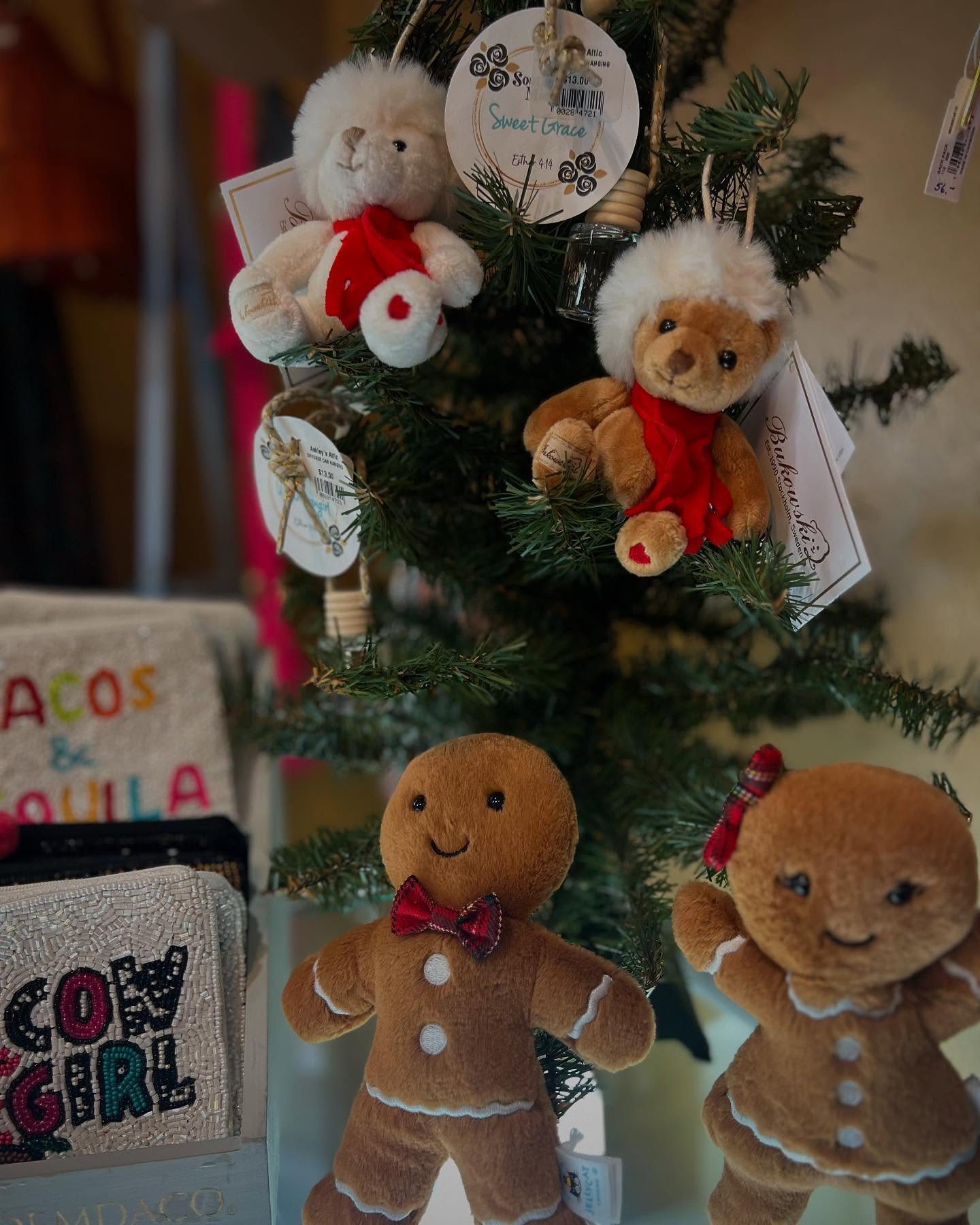 Small decorated Christmas tree with plush teddy bears, ornaments, and a festive sign.