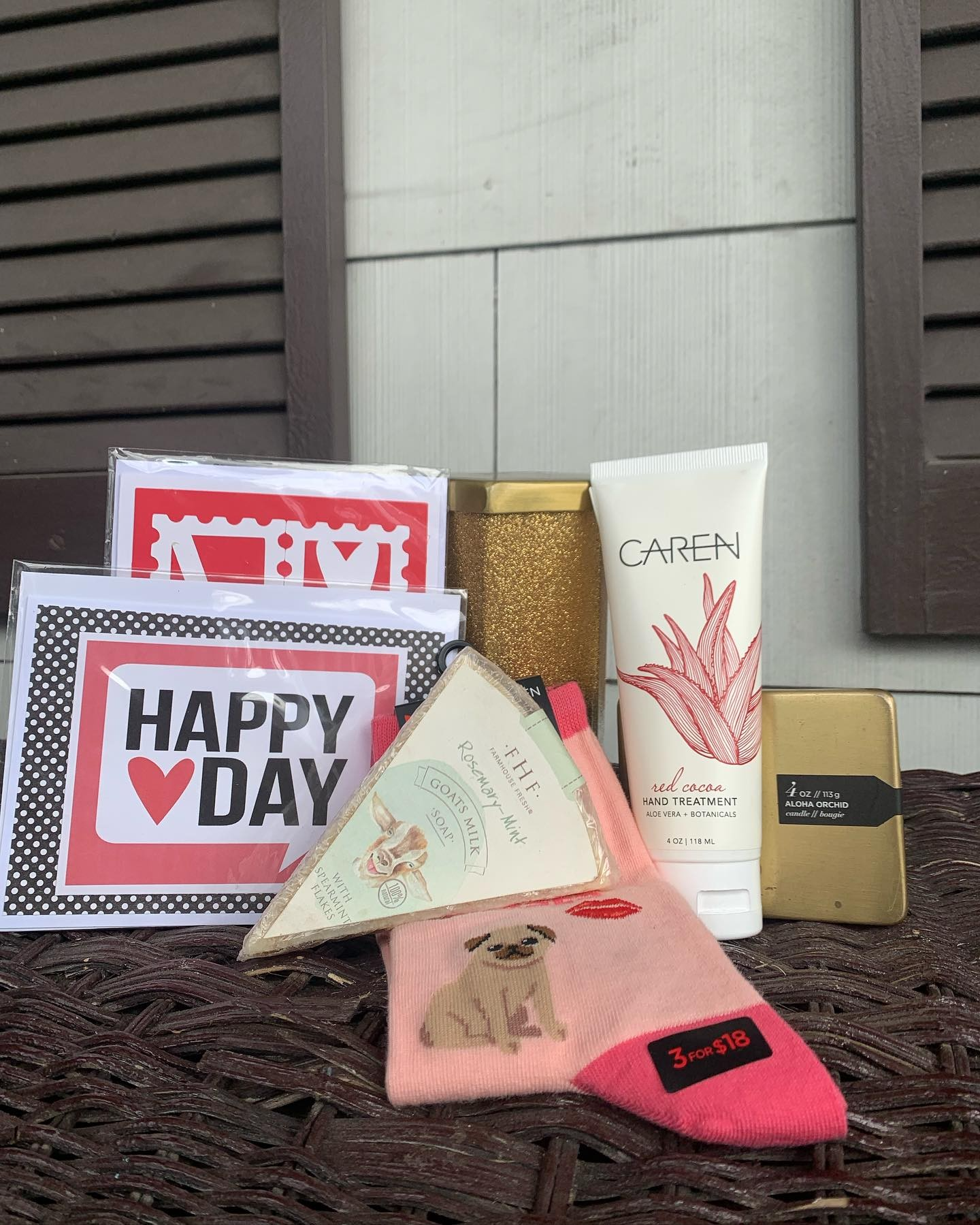Gift arrangement on a table with a “Happy Day” card, cookies, a box, and pink patterned packages.