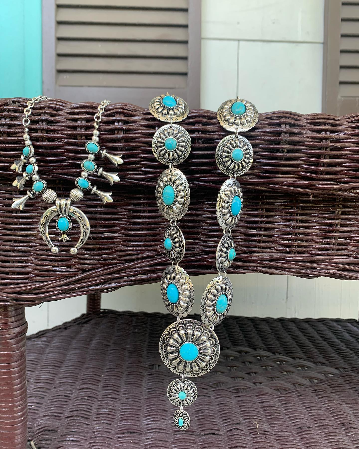 Turquoise and silver statement jewelry necklace and bracelet displayed on a woven chair outdoors