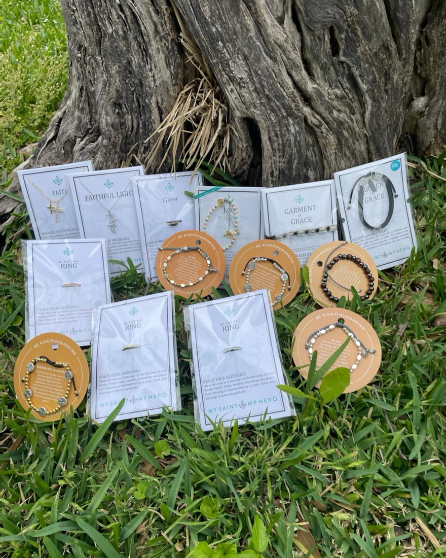 Craft fair display of beaded and woven bracelets on a tree trunk beside grass