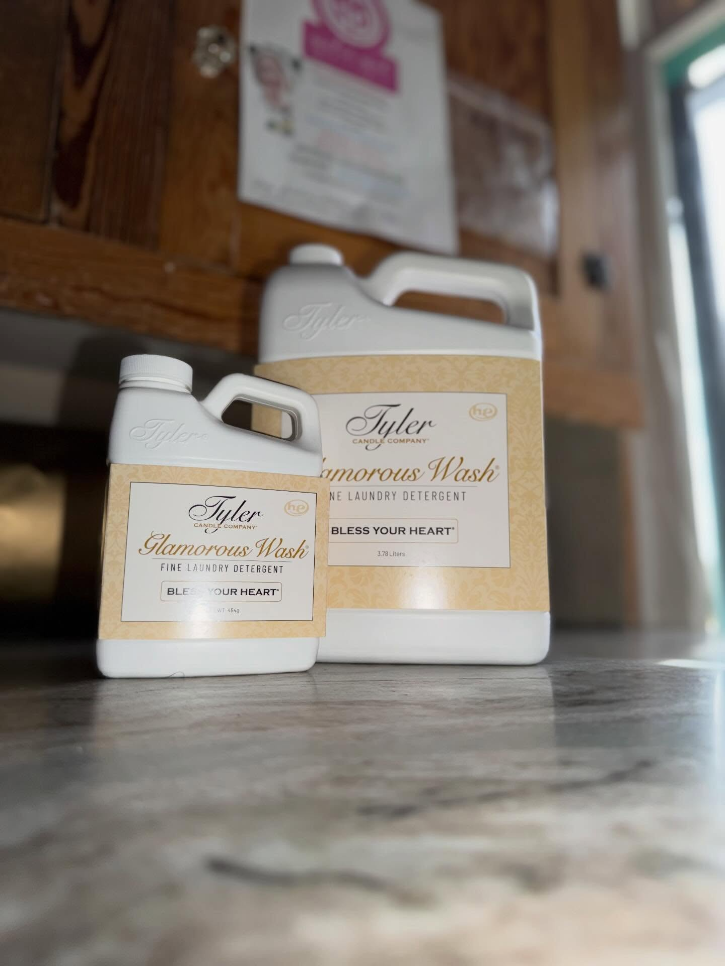 Two white laundry detergent jugs on a kitchen counter, one small and one large, with beige labels.