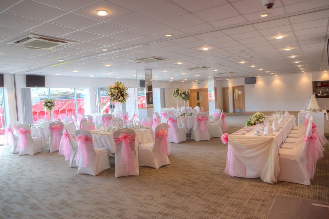Banquet hall set for an event with pink chair sashes and white tablecloths