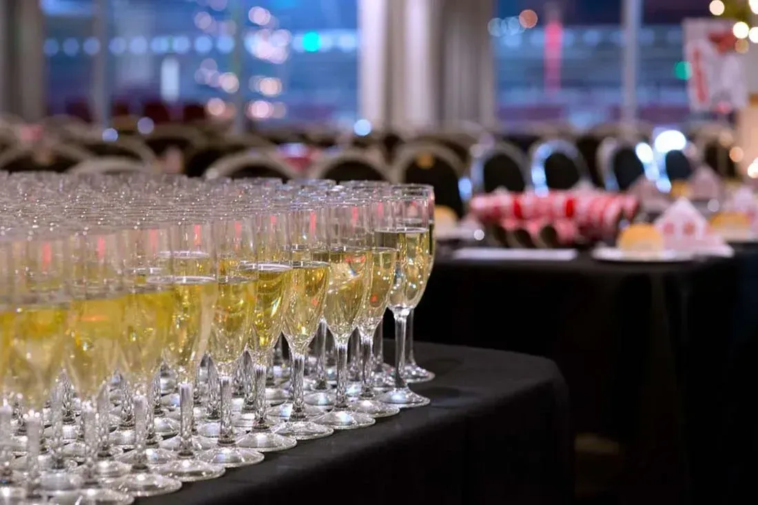 Rows of champagne flutes with yellow drinks on a black table at a banquet event