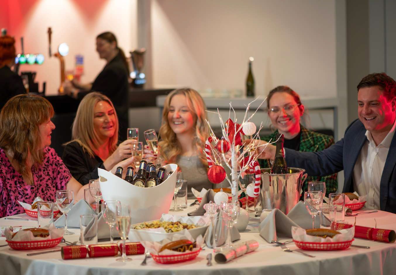 Guests at a decorated dinner table smiling and toasting with glasses at a festive event