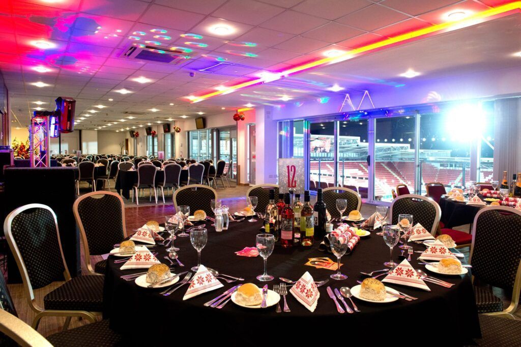 Elegant banquet hall with round dinner tables set for an event under colorful ceiling lights.