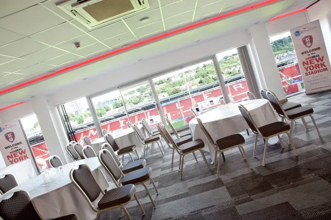Bright restaurant dining area with empty tables and chairs by large windows and red ceiling lights