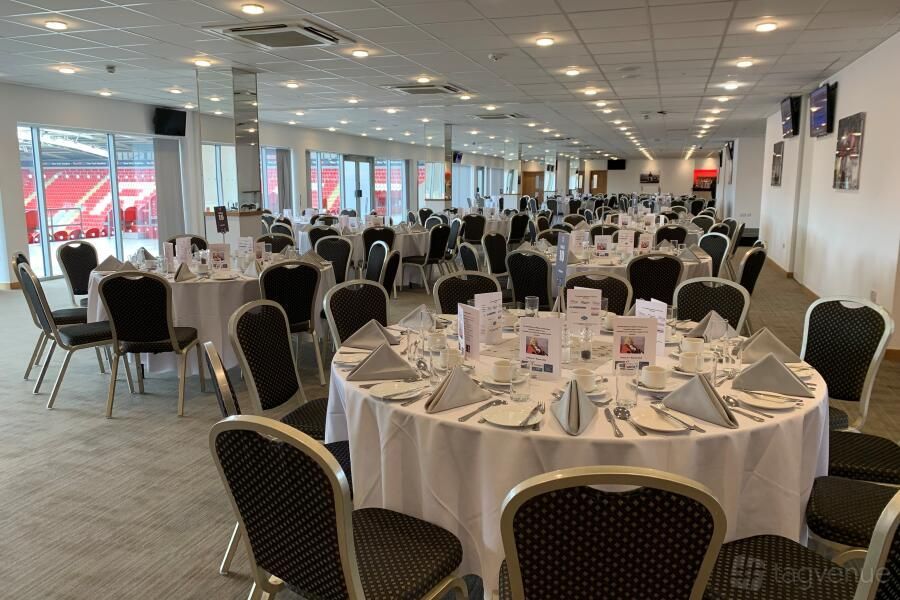 Banquet hall with round tables set for dining under bright ceiling lights