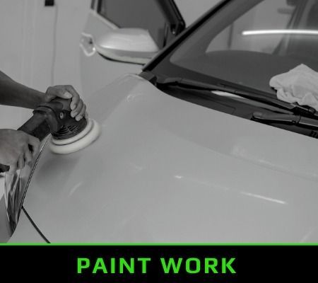 Car buffing a car hood in a paint shop, with “PAINT WORK” text below