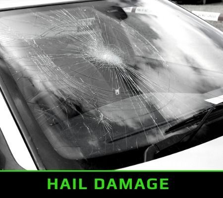 Car windshield with cracked glass from hail damage, shown in black and white.