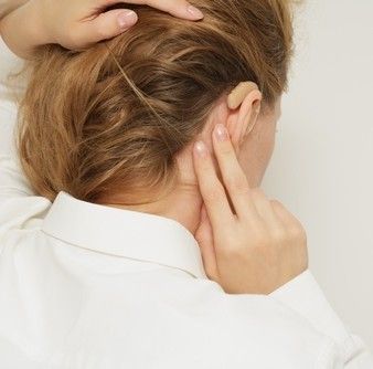 Person holding the back of their head, suggesting pain or tension or early signs of hearing loss