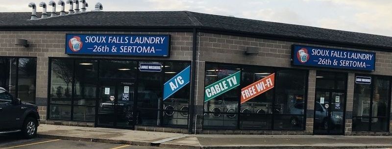A car is parked in front of a laundromat.