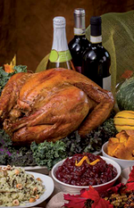 Roasted turkey with cranberry sauce, stuffing, and squash on a festive table, with wine bottles in the background.