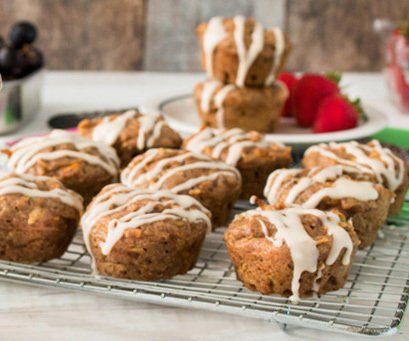 Carrot muffins with icing drizzle on a cooling rack, strawberries and blueberries in the background.
