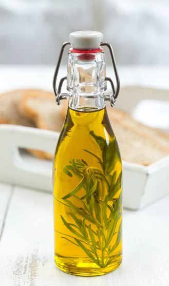 Bottle of olive oil with rosemary sprigs, next to a tray of bread.