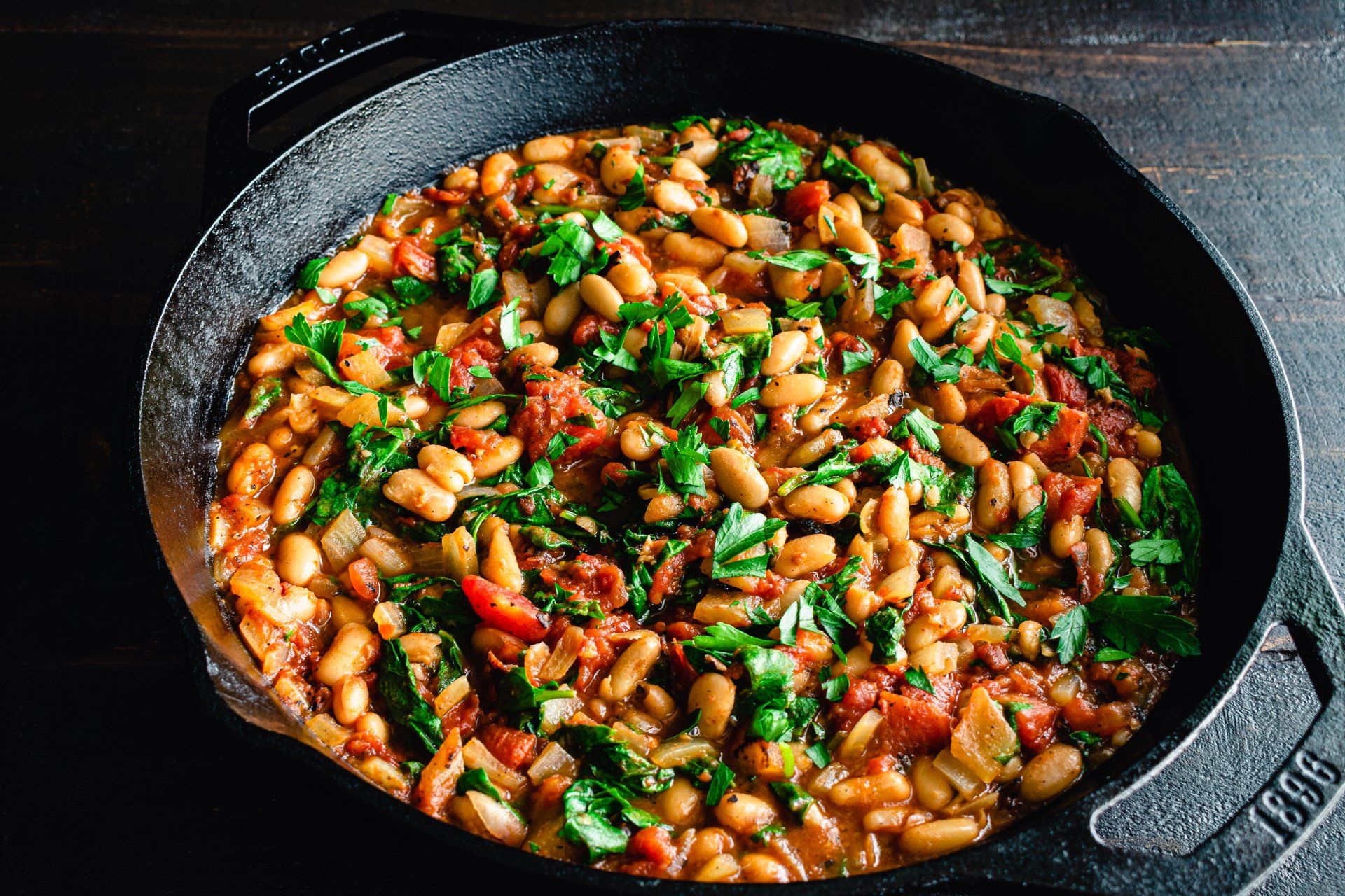 Beans simmered in tomato sauce and herbs in a cast iron skillet.
