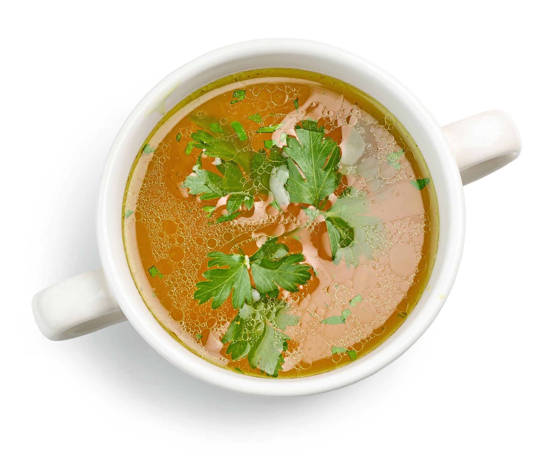 Overhead shot of a white soup bowl filled with clear broth, garnished with parsley. The bowl has two handles.