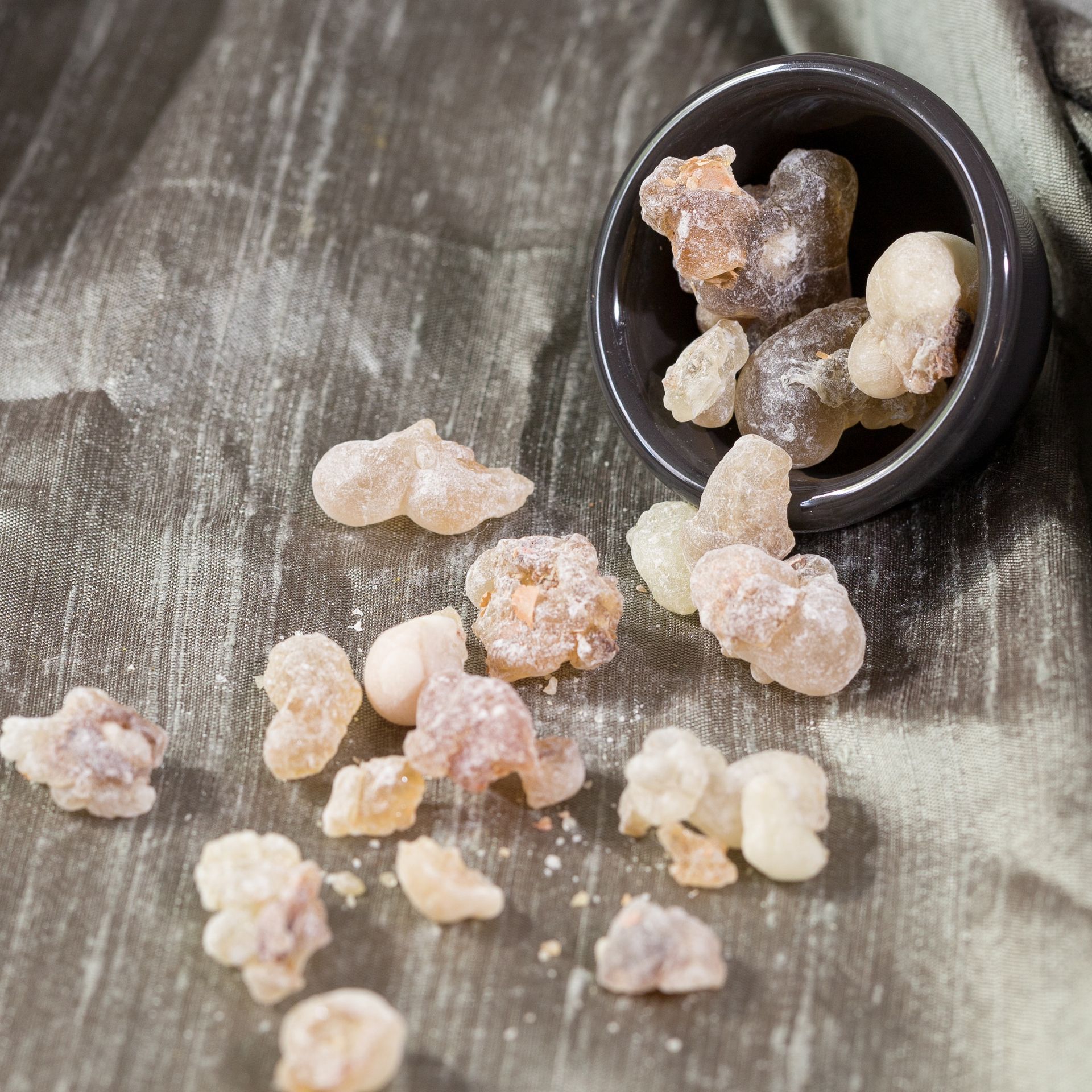 Bowl of pale, translucent, crystallized lumps spilling onto a textured, gray-green surface.