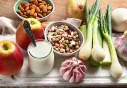 A tray with various healthy foods, including apples, almonds, beans, yogurt, onions, and garlic.