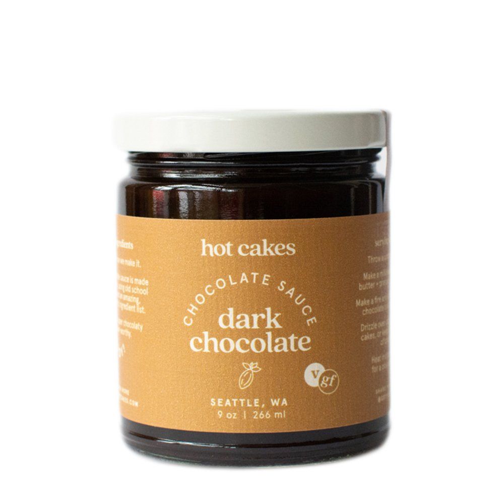 A jar of Hot Cakes dark chocolate sauce. The label is tan with dark brown text and a white lid. 