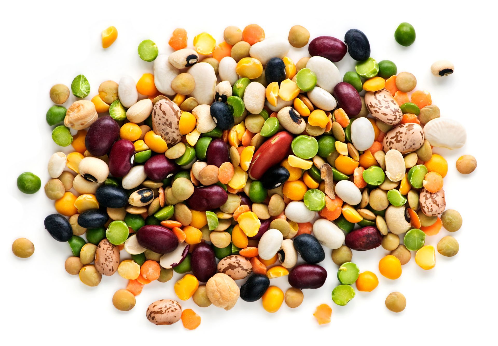 A colorful assortment of dried beans and lentils scattered on a white surface.