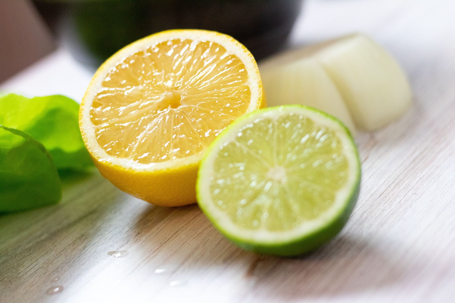 Lemon and lime halves on a cutting board next to onion slices and green pepper.