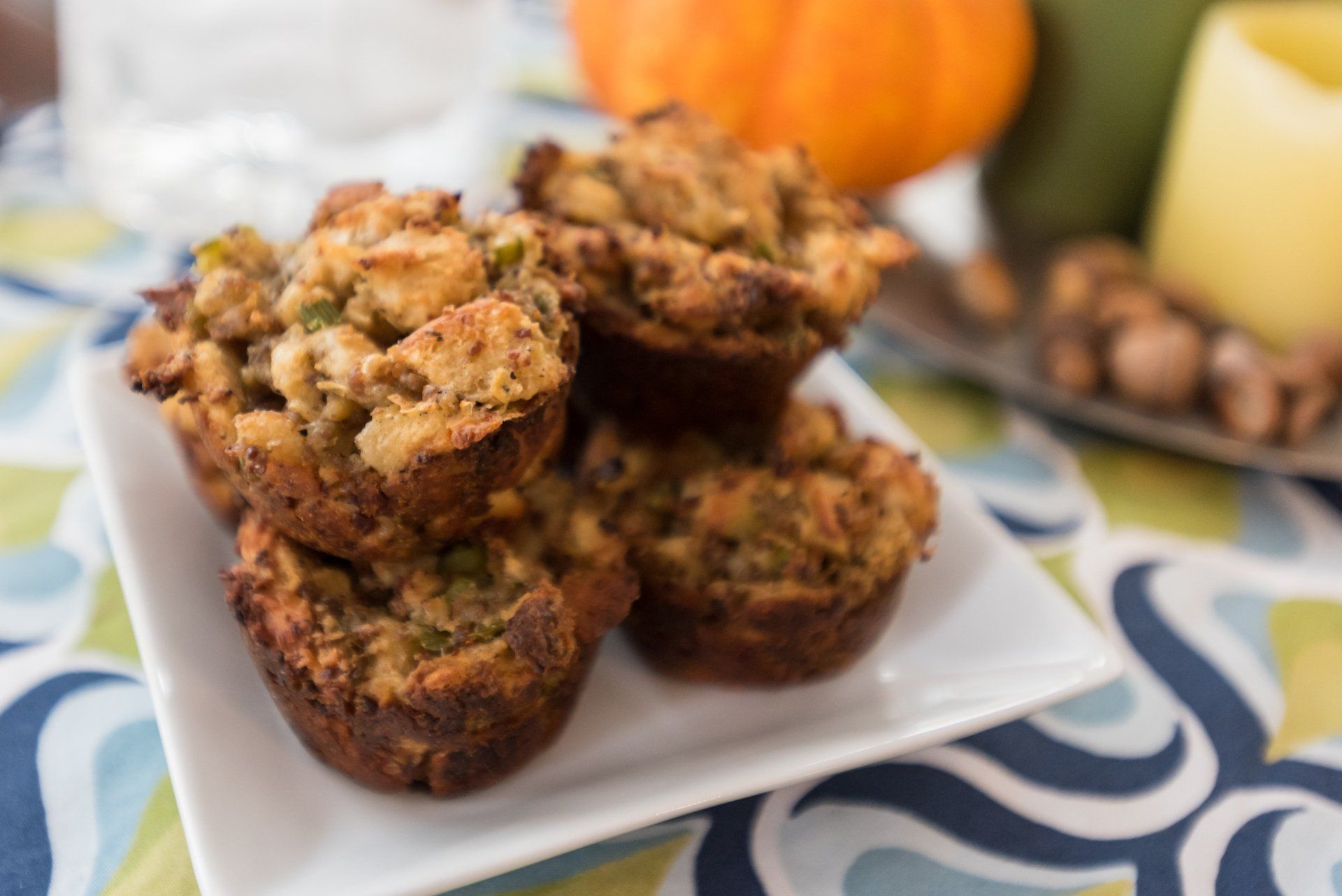 Savory stuffing muffins on a white plate, with blurred fall decor in background.