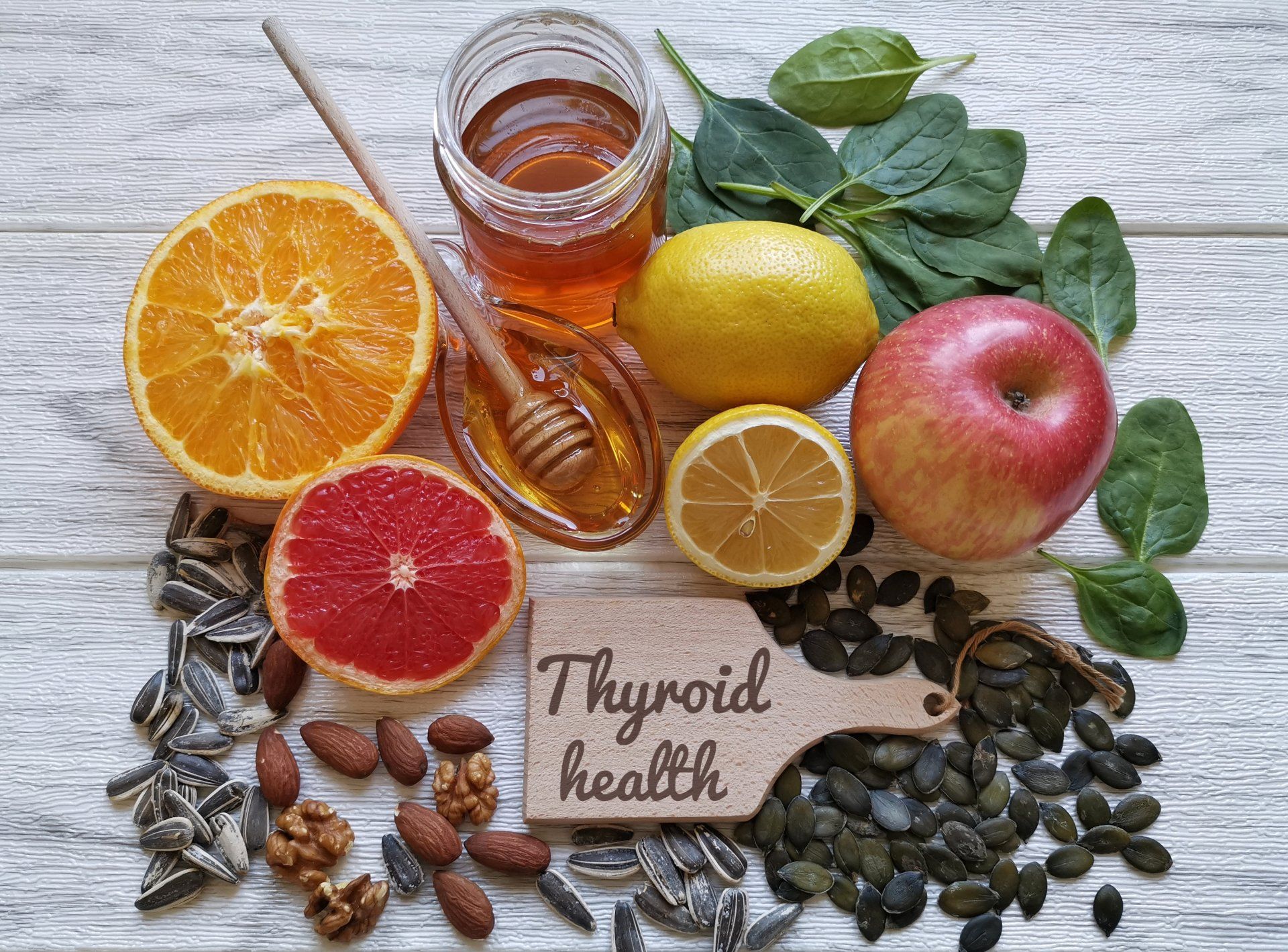 Fruits, seeds, and honey on a wooden surface, with a sign that reads