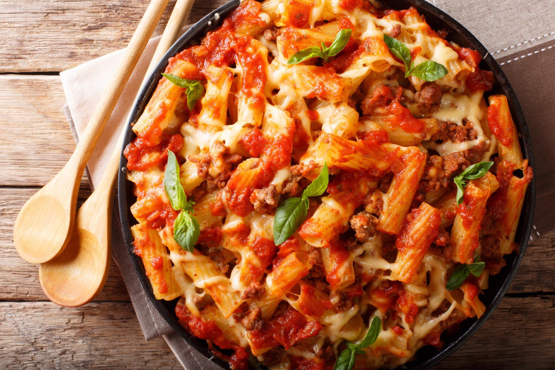 Baked pasta dish with cheese and tomato sauce, garnished with basil.