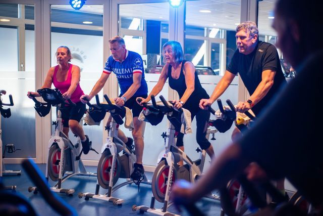 Een groep mensen fietst op een hometrainer in een sportschool.