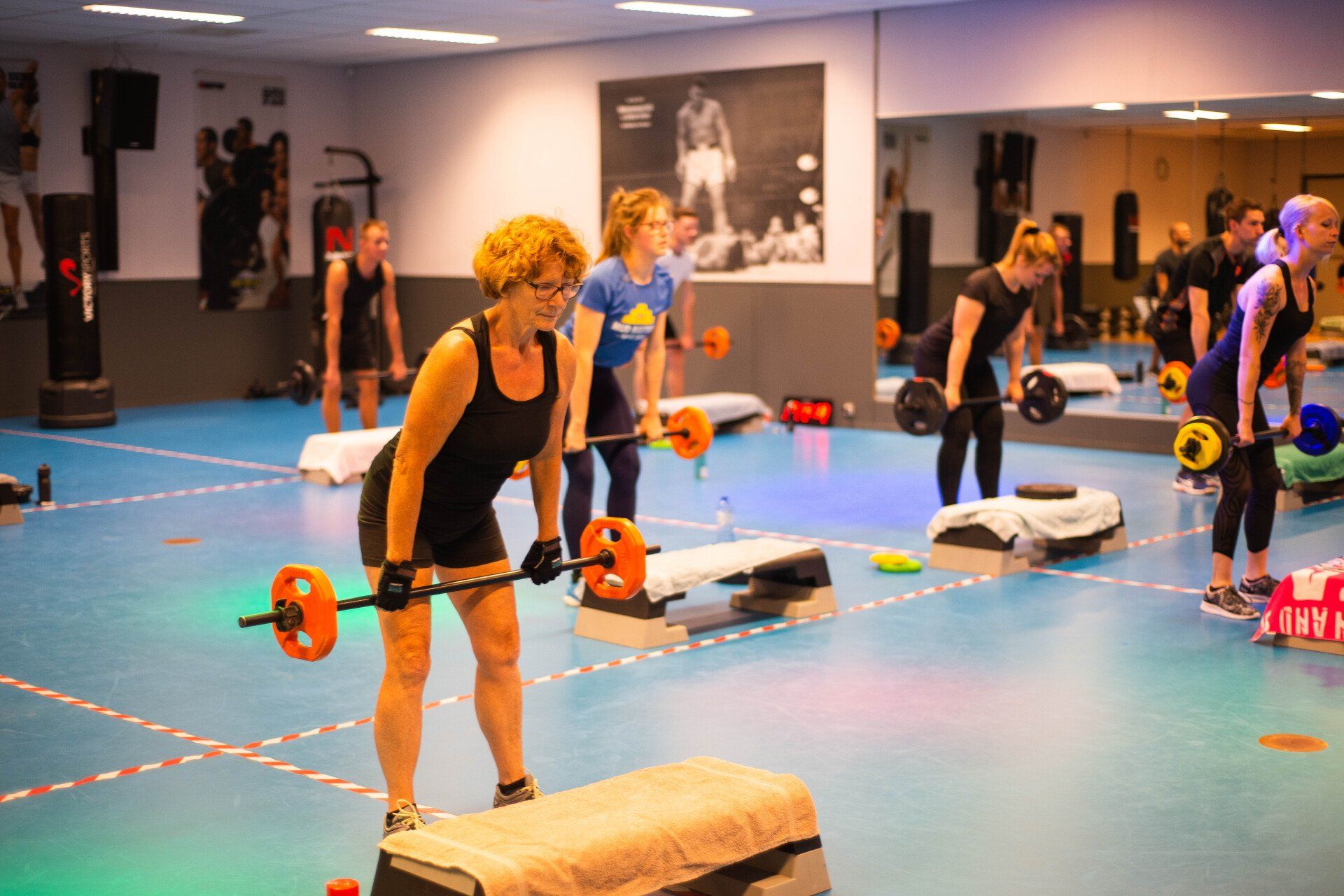 Mensen in een gymles tillen gewichten. Indoor gym met spiegelwand.