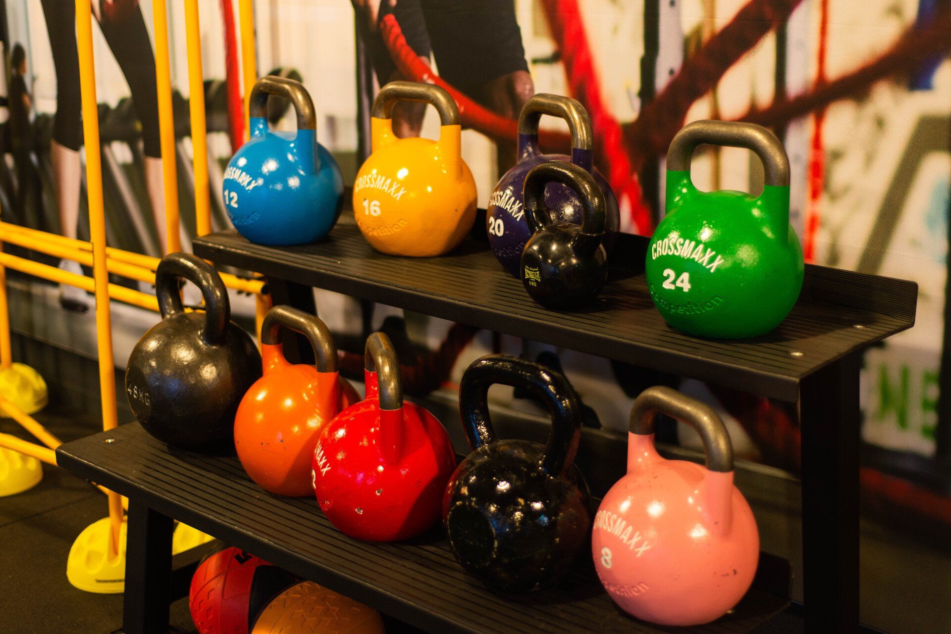 Man wordt in de sportschool door een trainer geholpen bij het doen van een dumbbell chest press.